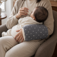 Coussin de bras gris utilisé par un adulte qui donne le biberon à bébé.