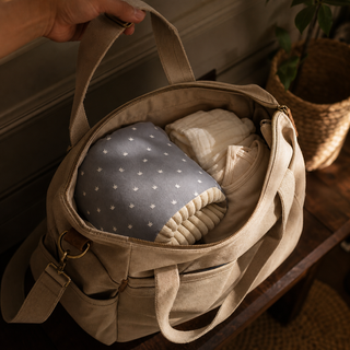 Coussin de bras à couronnes rangé avec les affaires de bébé dans un sac ouvert.