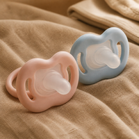 Sucette silicone bébé Bibimood rose et bleue sur linge crème