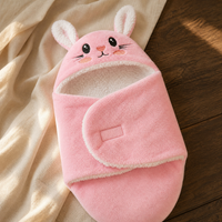 Couverture cocon lapin rose fermée, posée sur un tissu clair.